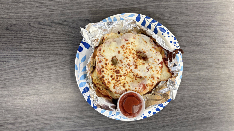 Sam's Club pizza pretzel with marinara sauce cup on paper plate on table