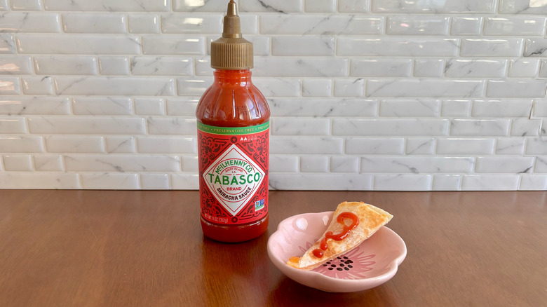 Tabasco Sriracha sauce bottle next to quesadilla slice