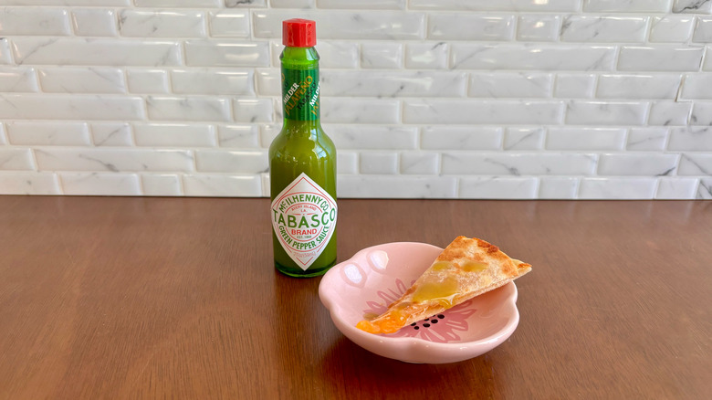 Tabasco green pepper sauce bottle next to quesadilla slice