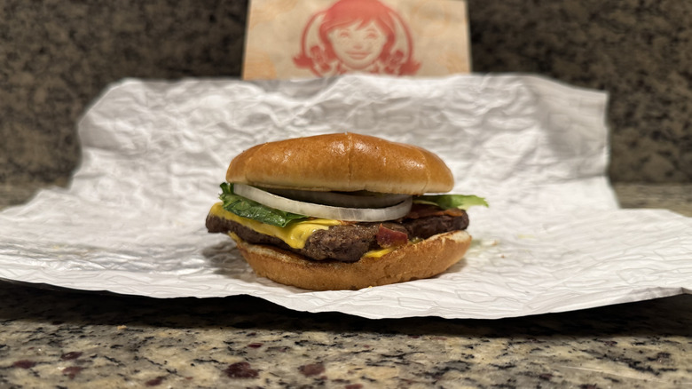 Big bacon classic burger in Wendy's wrapper on counter