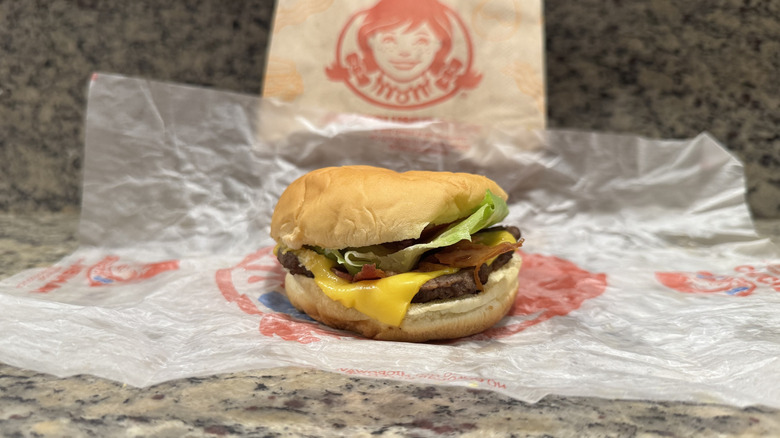 Jr. bacon cheeseburger in Wendy's wrapper on counter
