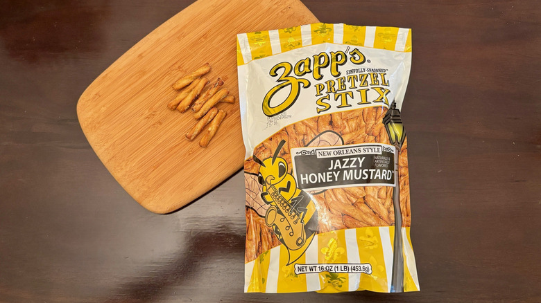 Bag of Jazzy Honey Mustard Pretzel Stix with stix on wooden board