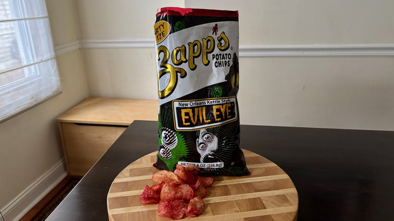 Bag of Zapp's Evil Eye chips and loose chips on cutting board