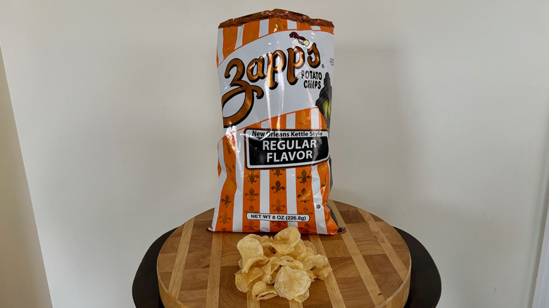 Bag of Regular Zapp's potato chips on table with chips spread