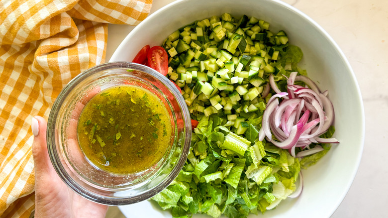 adding dressing to salad bowl