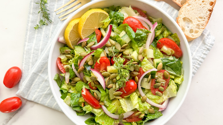 serving bowl of romaine tomato salad with bread