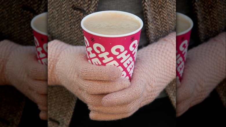 dunkin chai oatmilk latte held in gloved hands