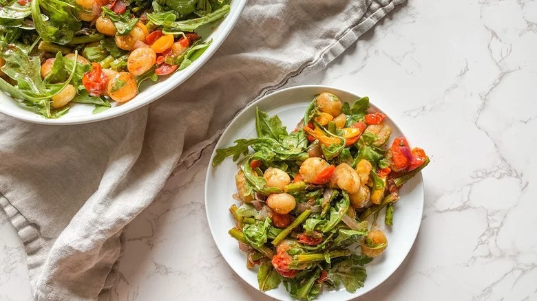 A bowl of cooked greens with toasted brown gnocchi