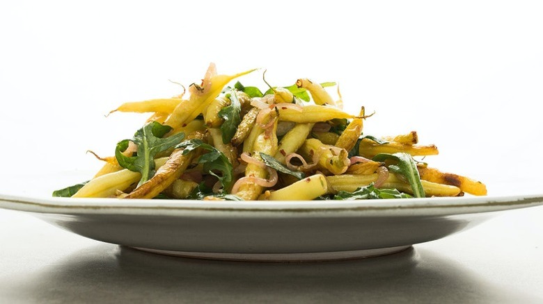 Yellow beans with green arugula on a white plate