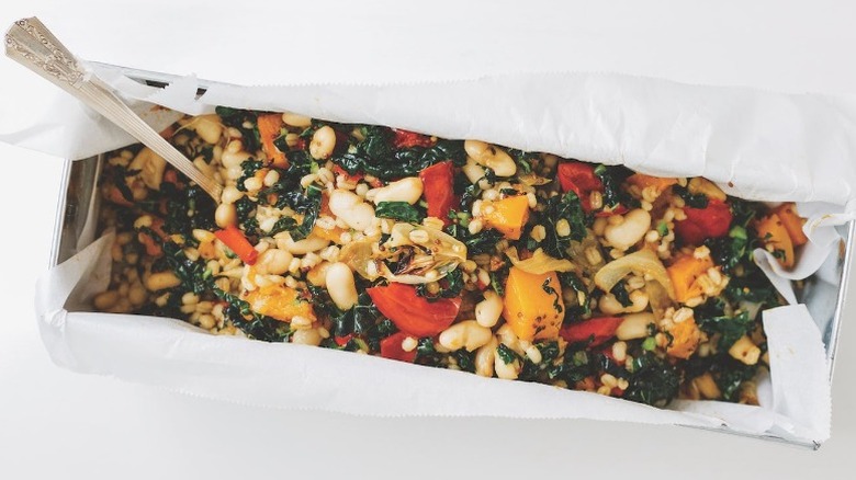 A long pan filled with colorful vegetables and barley
