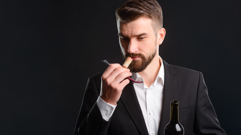 man smelling wine bottle cork