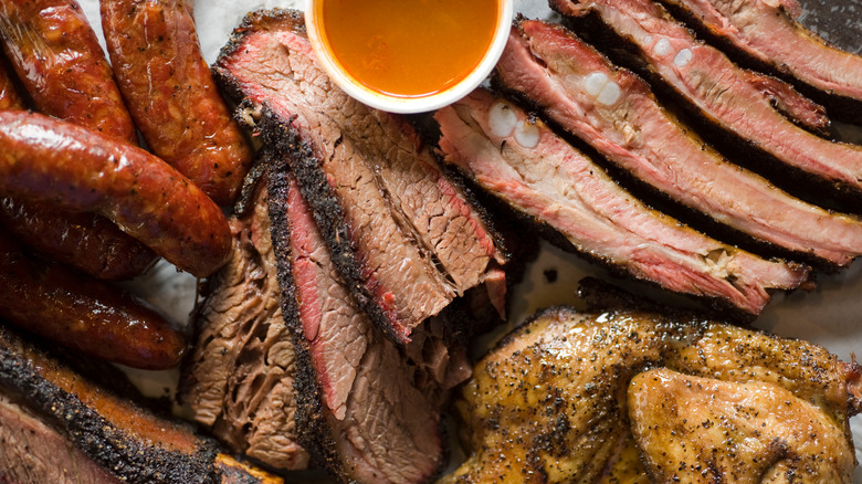 Barbecue catering platter with variety of meats. Traditional Texas BBQ: Beef brisket, beef ribs, pork ribs, sausage links, black pepper roasted chicken, and turkey served with homemade sauce.