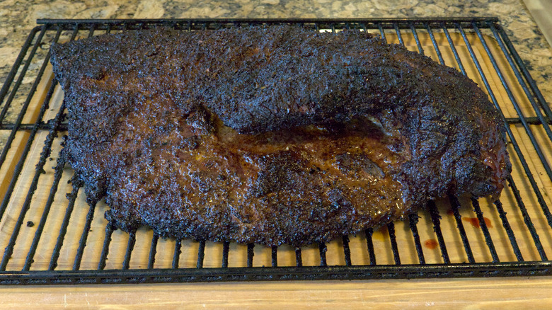 Brisket resting on a wire rack and wooden cutting board