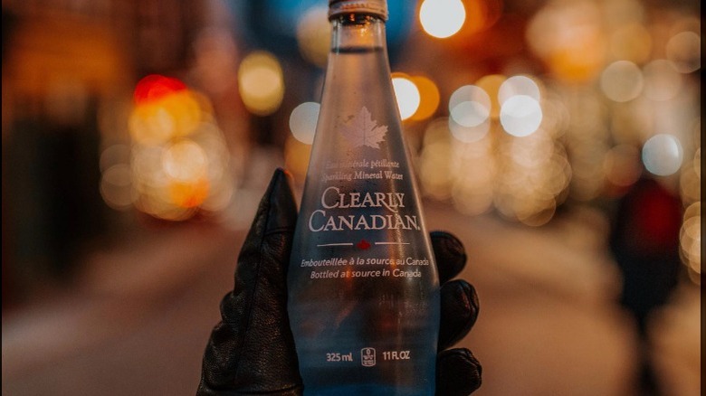 Hand holding bottle with city lights