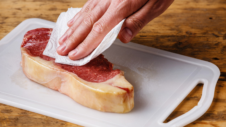 Wiping steak with paper towel