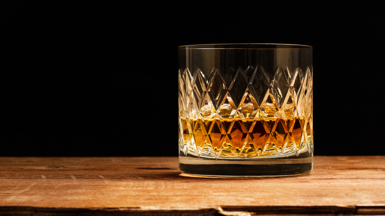 A glass of whiskey on a wooden surface