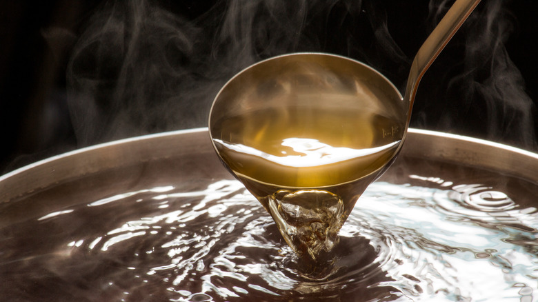 Metal ladle pouring steaming liquid 