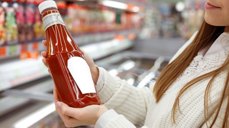 Woman holding ketchup bottle in supermarket