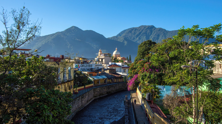 A view shows a river passing through a town in Veracruz with mountains in the background.