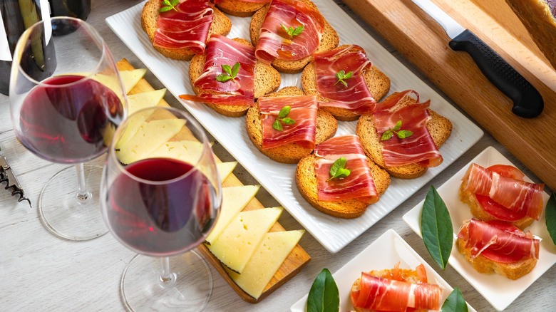 spanish ham crostini with cheese and red wine glasses