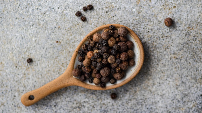 black peppercorns on wooden spoon