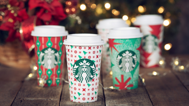 Starbucks holiday cups with festive decorations and lights