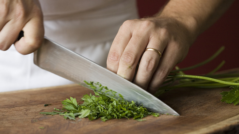 Chef cuts herbs on board