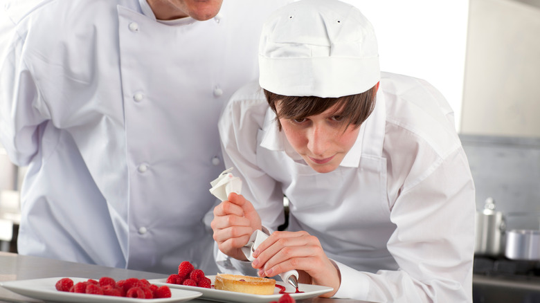 young chef piping raspberry sauce