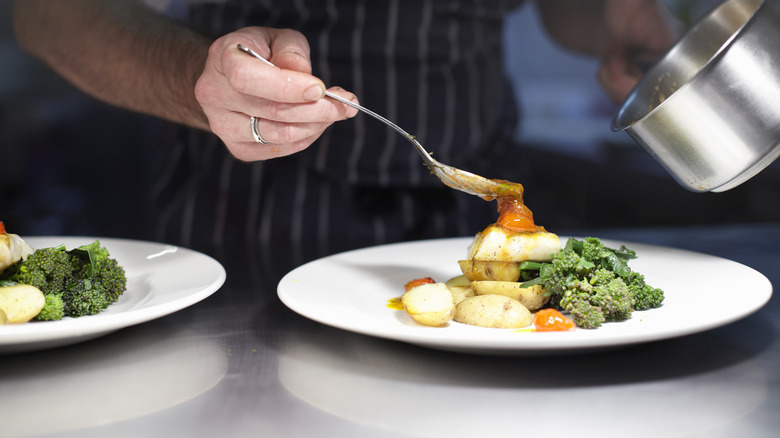 Chef pours sauce on plate