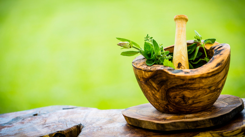 Wooden mortar and pestle with herbs