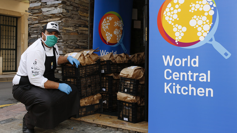 Chef standing next to World Central Kitchen sign with meals