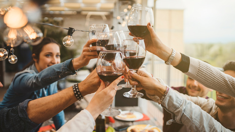 People clinking red wine glasses