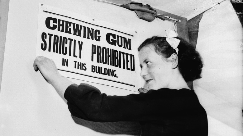 Woman hanging chewing gum ban sign