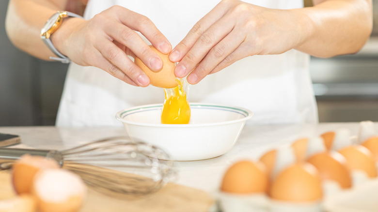 Person cracking eggs into bowl