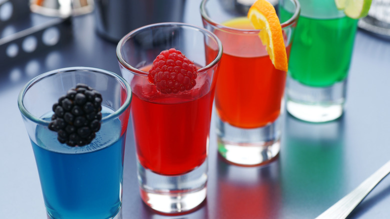 Four multicolored jello shots garnished with fruit