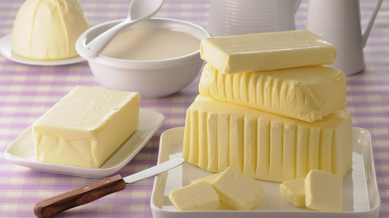 Plates of stacked butter with a knife and some cut pieces