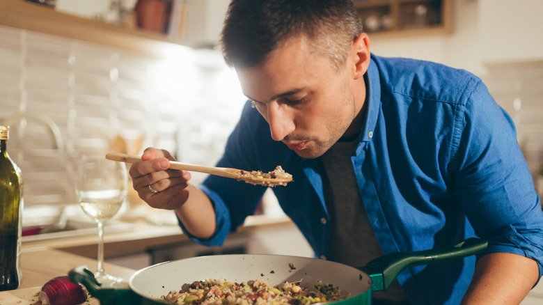 Person tasting risotto frying pan