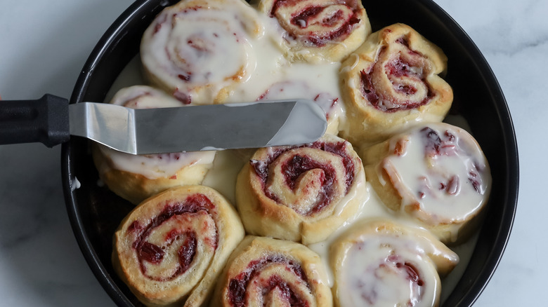 spreading sugar glaze on rolls