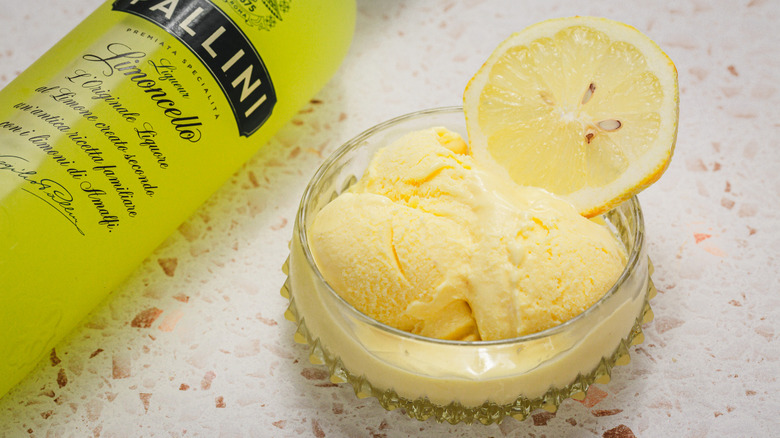 Close up on 1 serving of lemon gelato alongside limoncello bottle