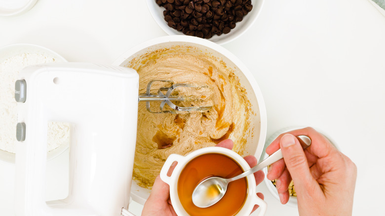 Person spoons vanilla into batter