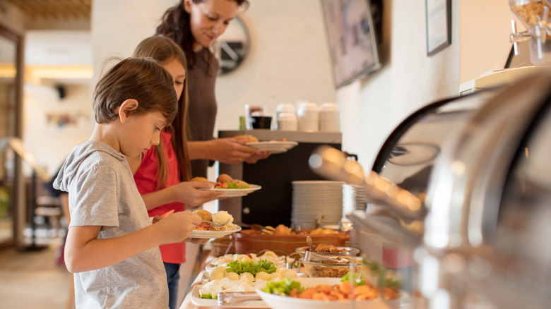 family of three helping themselves to a buffet