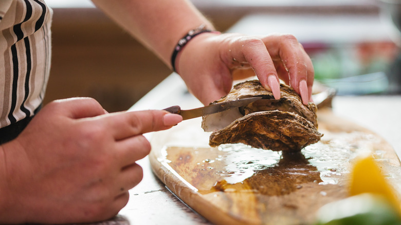 Person carving open a raw oyster