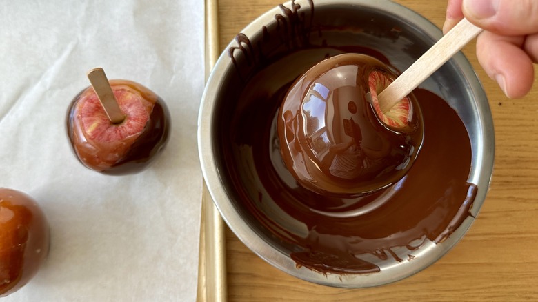 Dipping caramel apples into chocolate