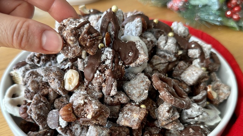 hand picking up muddy buddies in bowl