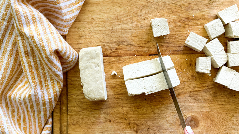 knife cubing tofu on board