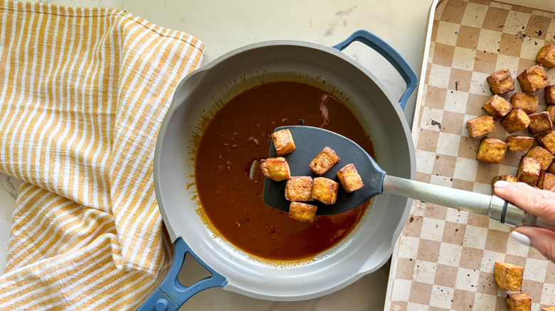 adding tofu to pan of sauce