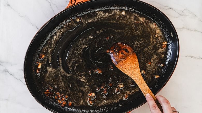 Whisking butter into sauce in a pan