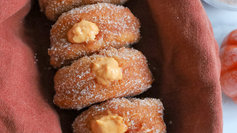 pumpkin filled donuts in basket with cloth napkin