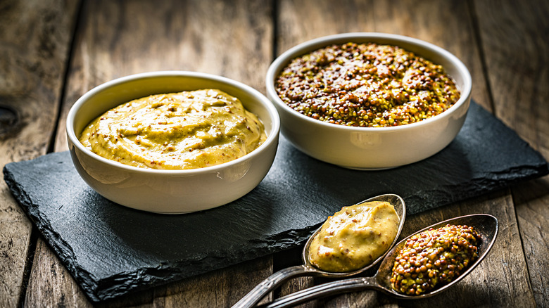 Two bowls of Dijon mustard with spoons