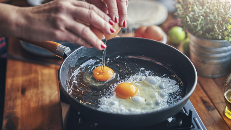 Cracking eggs in frying pan